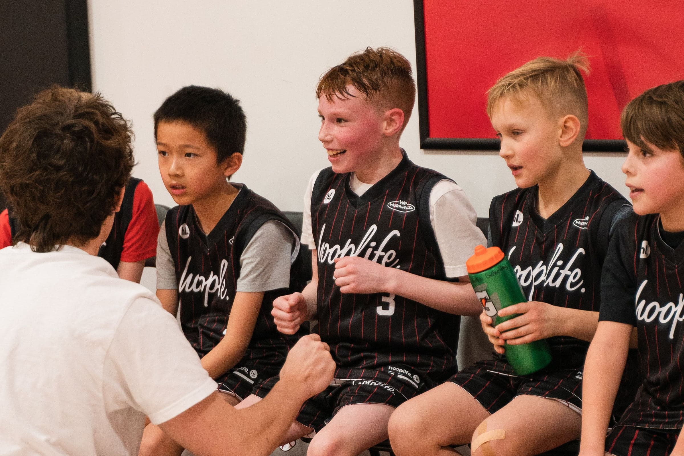 Young players on the bench with their water bottles at HoopLife in Regina