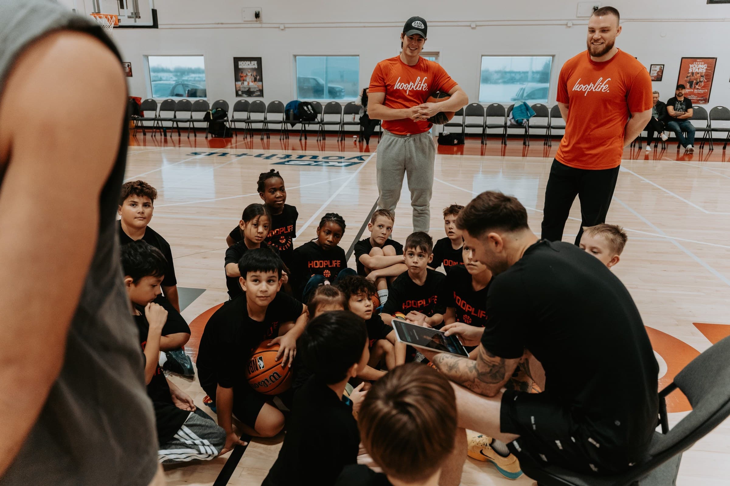 HoopLife coaches teaching a seated group of young players at the HoopLife Centre in Regina
