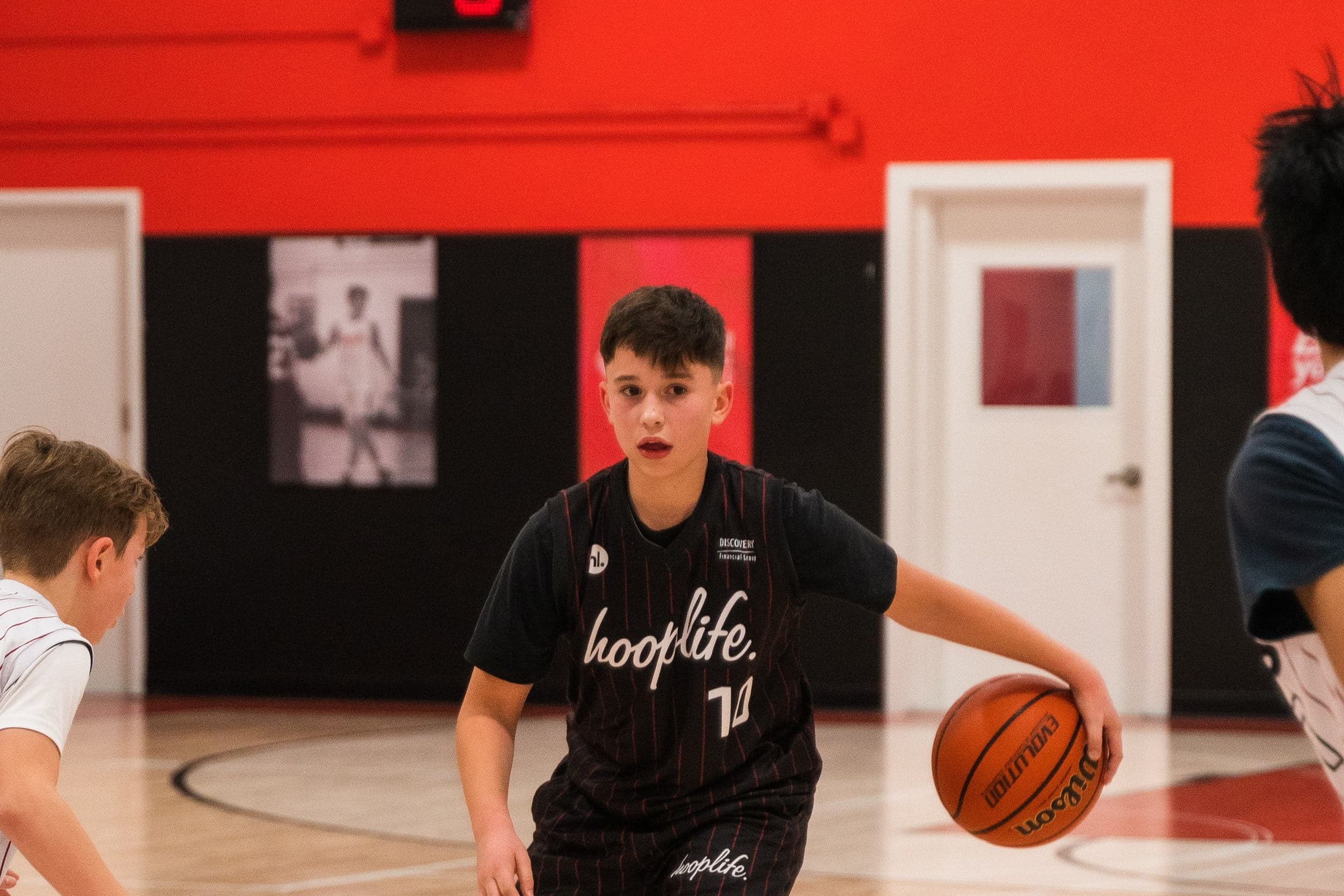 A player dribbling low in a HoopLife shirt on the court in Regina