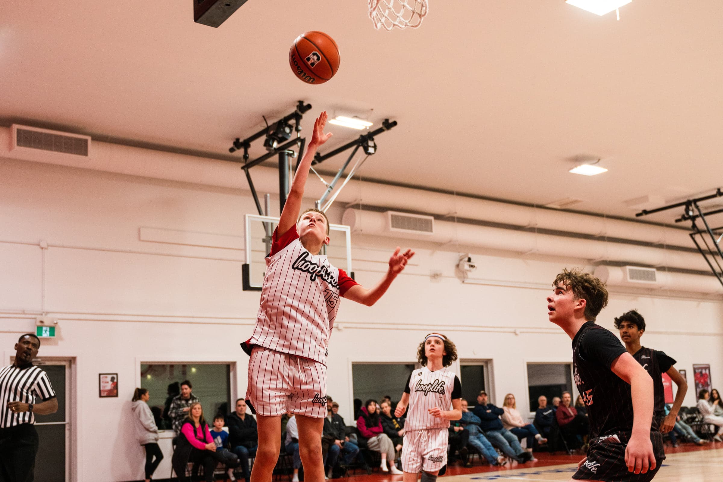 A player finishing a layup in front of a full crowd at HoopLife in Regina