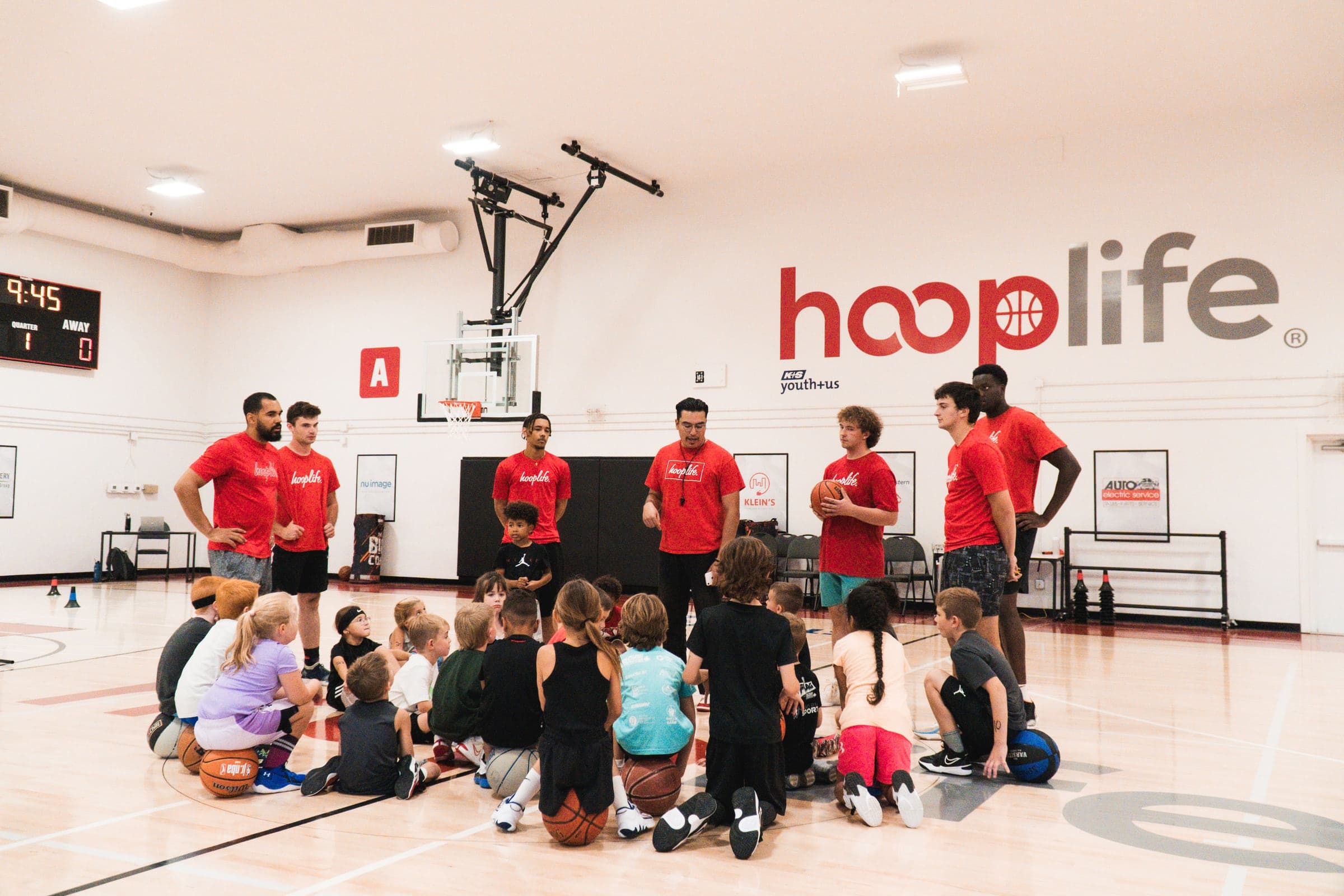 A gym full of kids sitting with their coaches under the HoopLife sign in Regina
