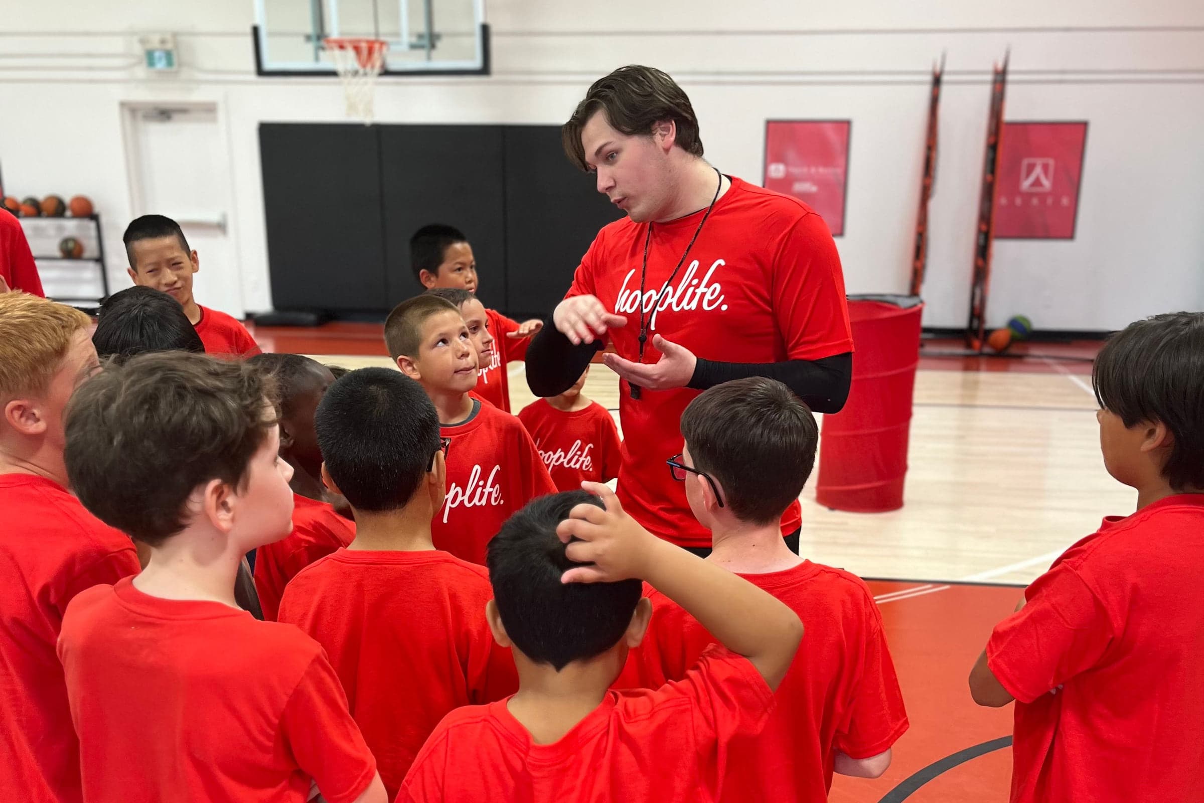 A HoopLife coach surrounded by young players listening in Regina