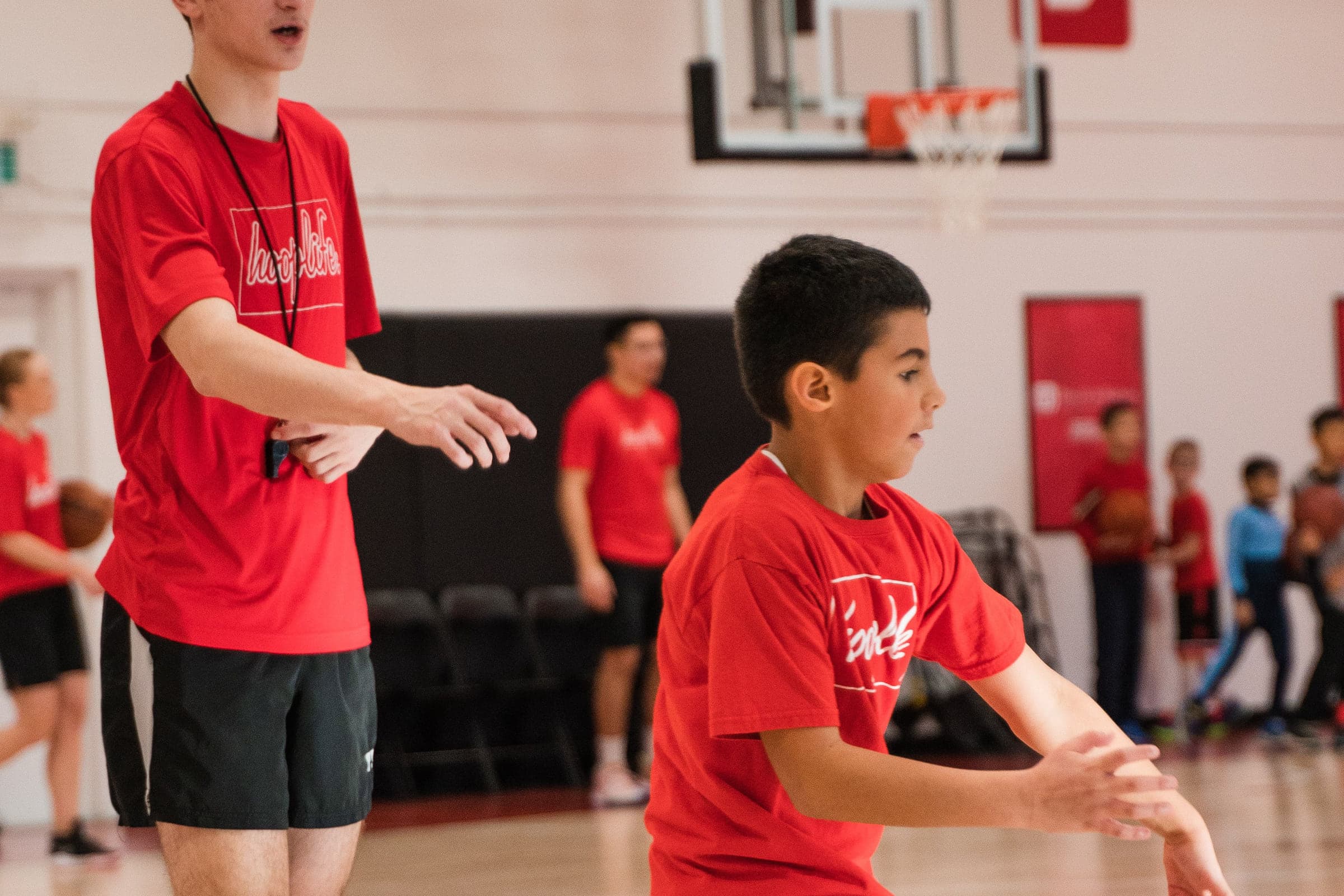 A young player working on his handles beside a coach at HoopLife in Regina