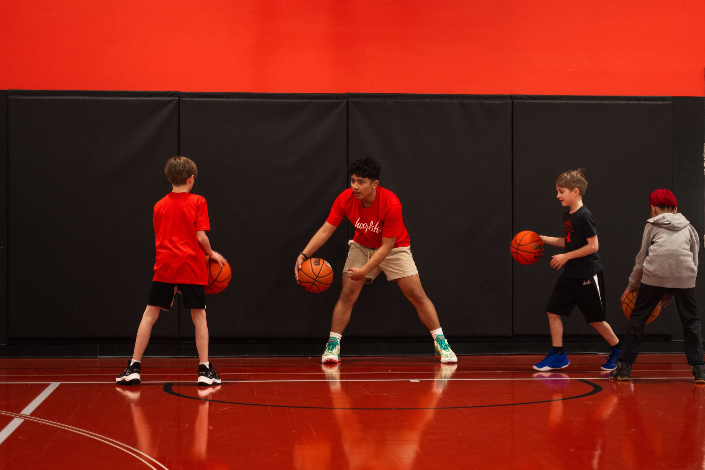 Young children dribbling basketballs on the court at the HoopLife Centre in Regina