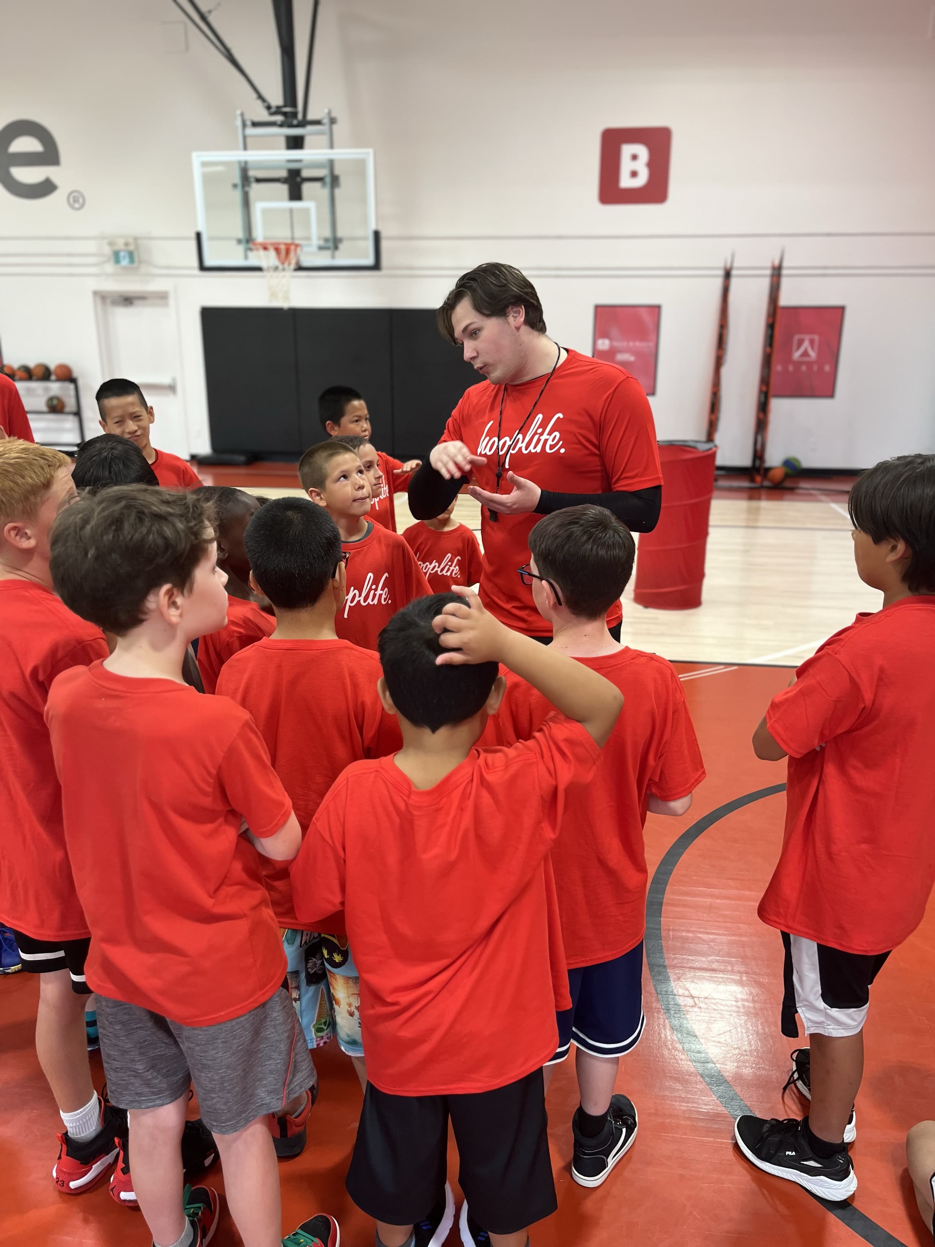 A HoopLife coach in a huddle with young players at the Regina gym