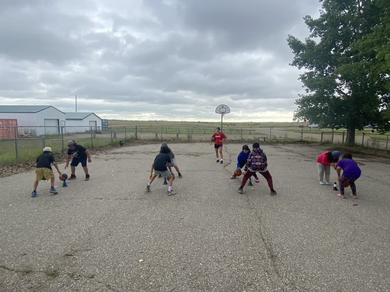 Dribble drills on the outdoor court at Birdtail Sioux under a prairie sky