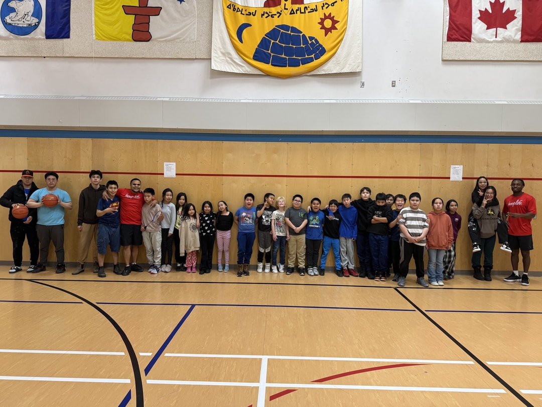 The whole Chesterfield Inlet camp lined up under the Nunavut flag after a HoopLife clinic