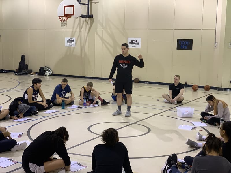 A HoopLife coach leading a teen mindset workshop with workbooks