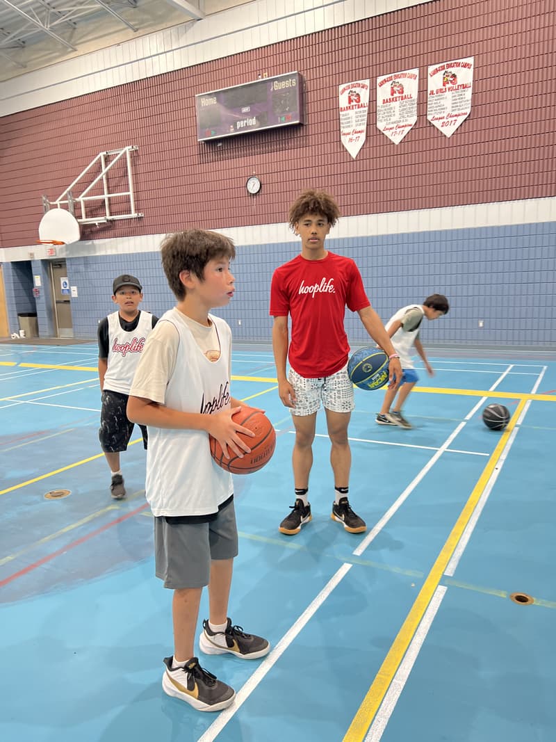 A HoopLife coach watching a camper line up his shot at the Kawacatoose clinic