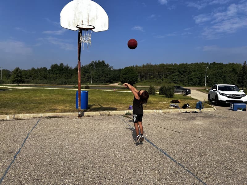Kids playing on the outdoor hoop at the Keeseekoowenin clinic