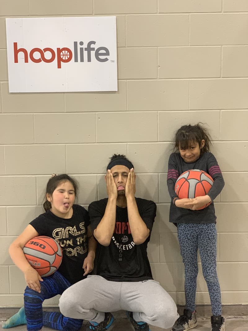 A HoopLife coach and two girls goofing around under the hooplife sign