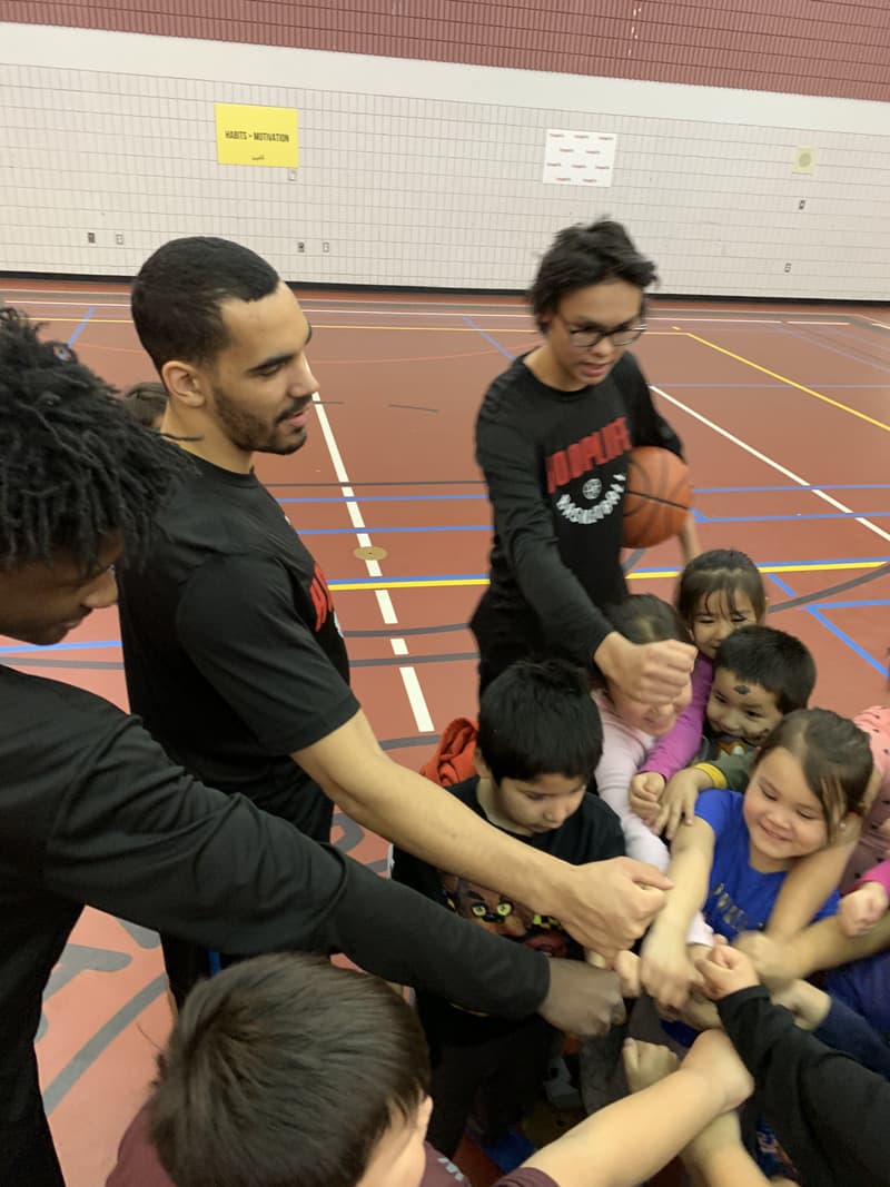 HoopLife coaches and Kinistin kids putting their fists into the huddle
