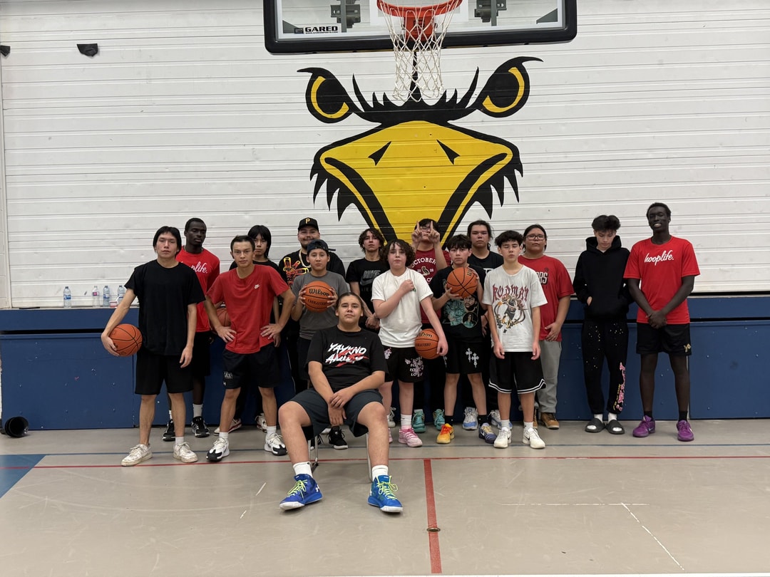 Piapot First Nation players under their gym's eagle mural with a HoopLife coach