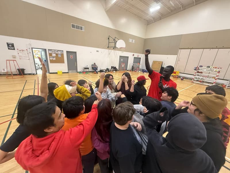 A HoopLife coach leading a mid-cheer huddle at the Sandy Lake clinic