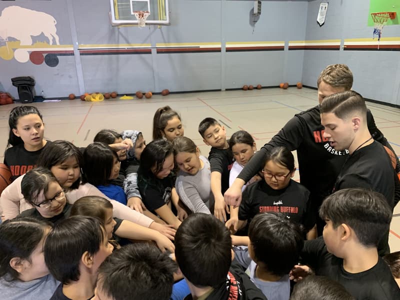 HoopLife coaches reaching into a big kids huddle at Standing Buffalo