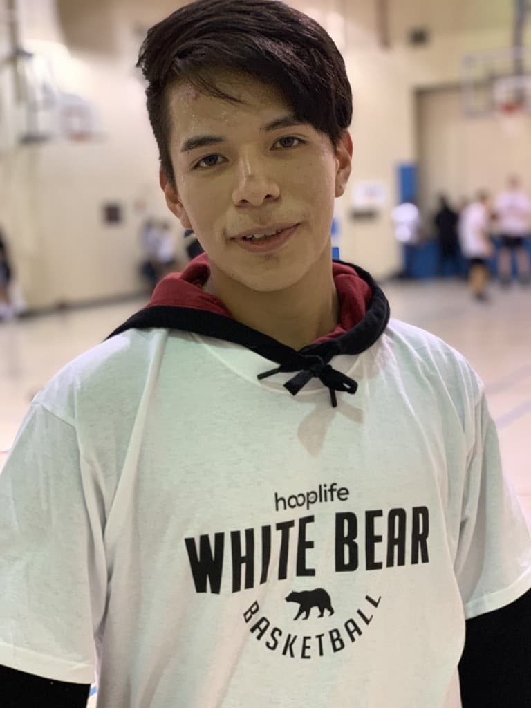 A smiling young player in a White Bear Basketball shirt at the HoopLife clinic