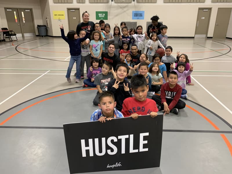 Whitecap Dakota kids and HoopLife coaches behind the HUSTLE banner