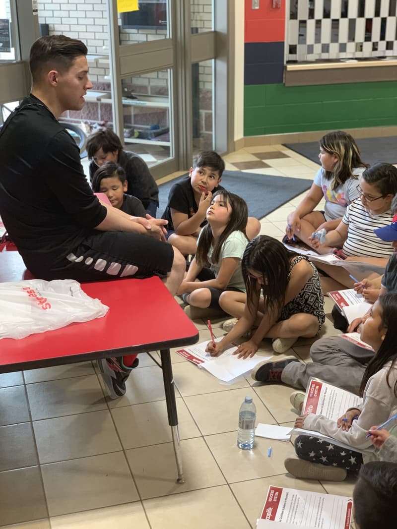 A HoopLife coach walking Whitecap kids through their Success System workbooks