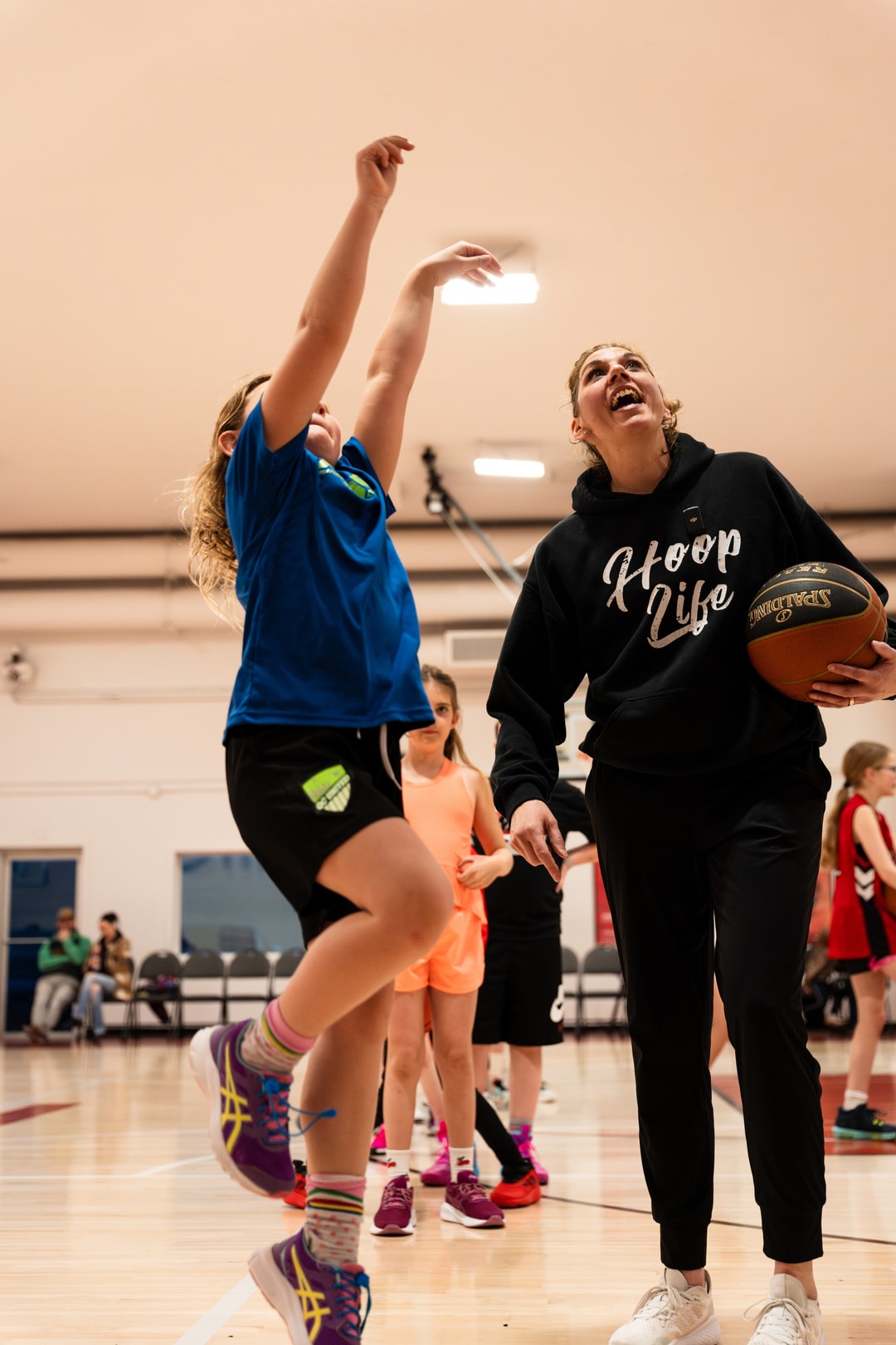A HoopLife coach watching a young player follow through on her shot