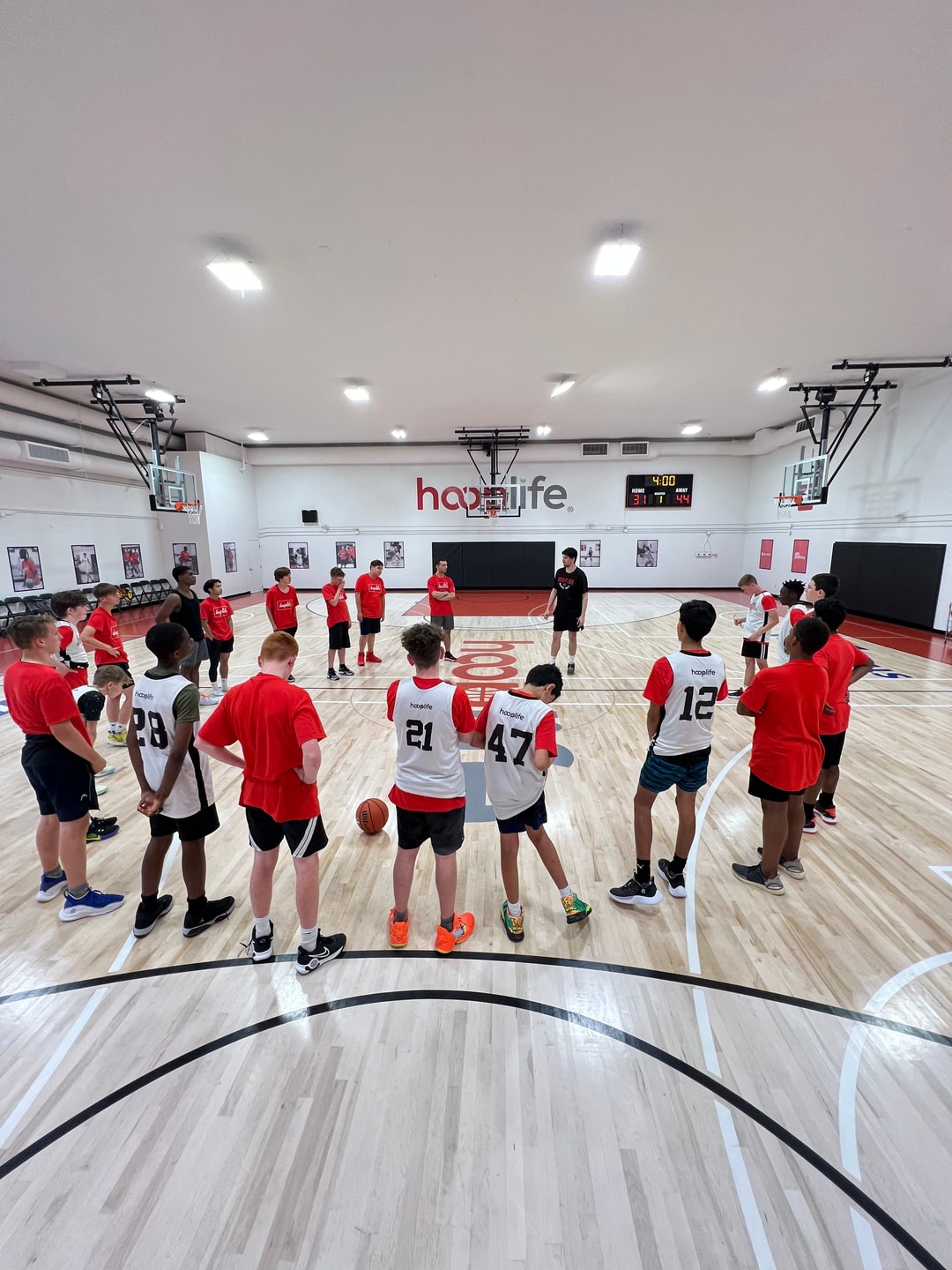 The full HoopLife gym in use, scoreboard and wordmark in view