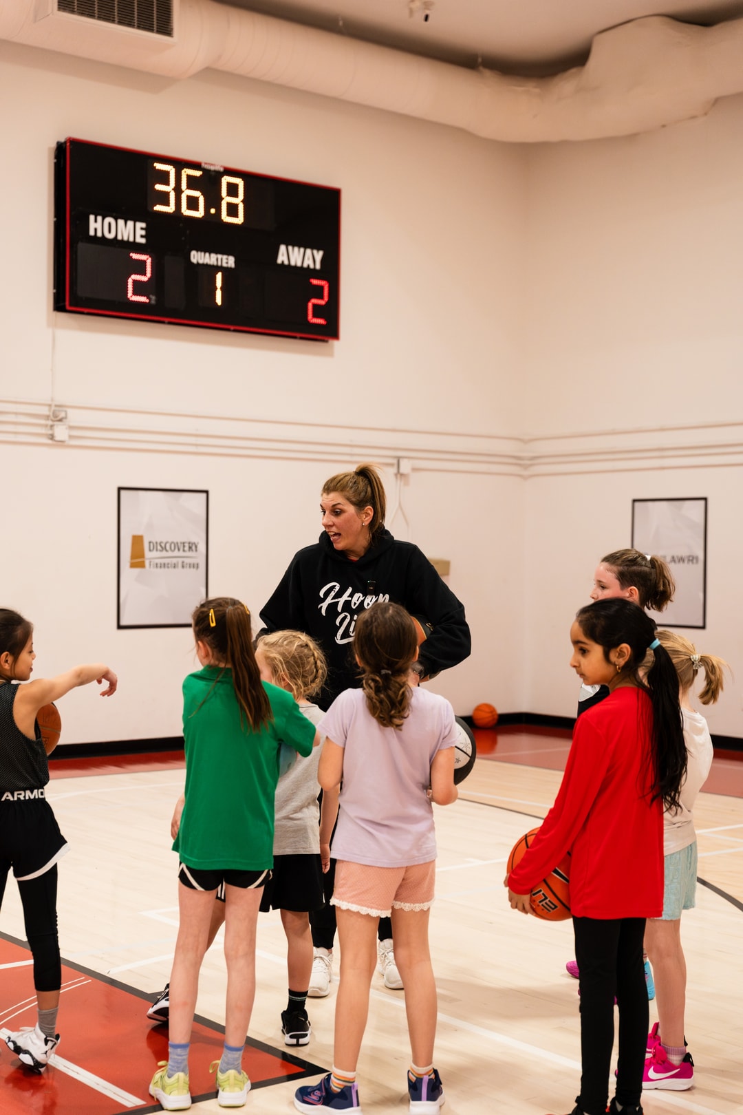 A woman coach directing a line of girls through a drill at a HoopLife girls only session