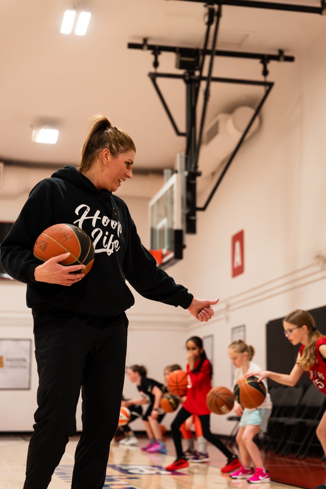 A woman coach encouraging girls mid-drill at a HoopLife girls only session