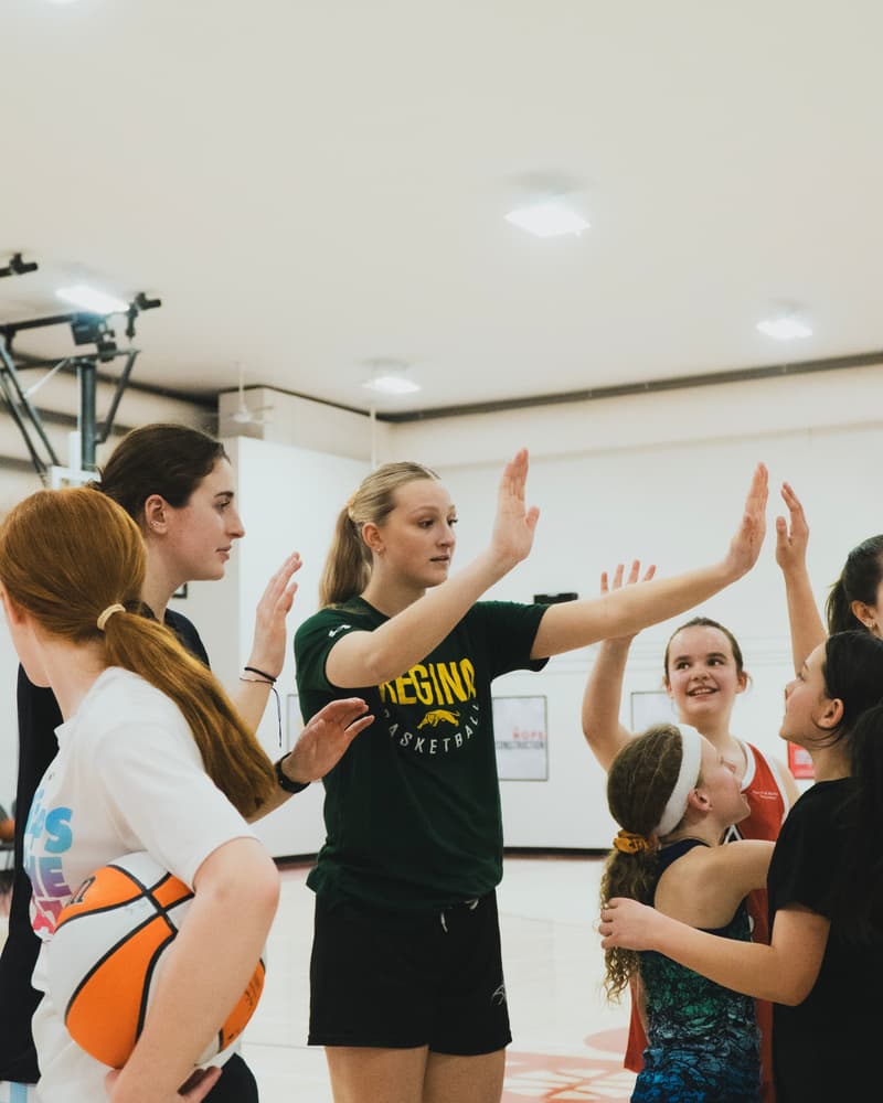 A woman coach high-fiving a player at a girls only session