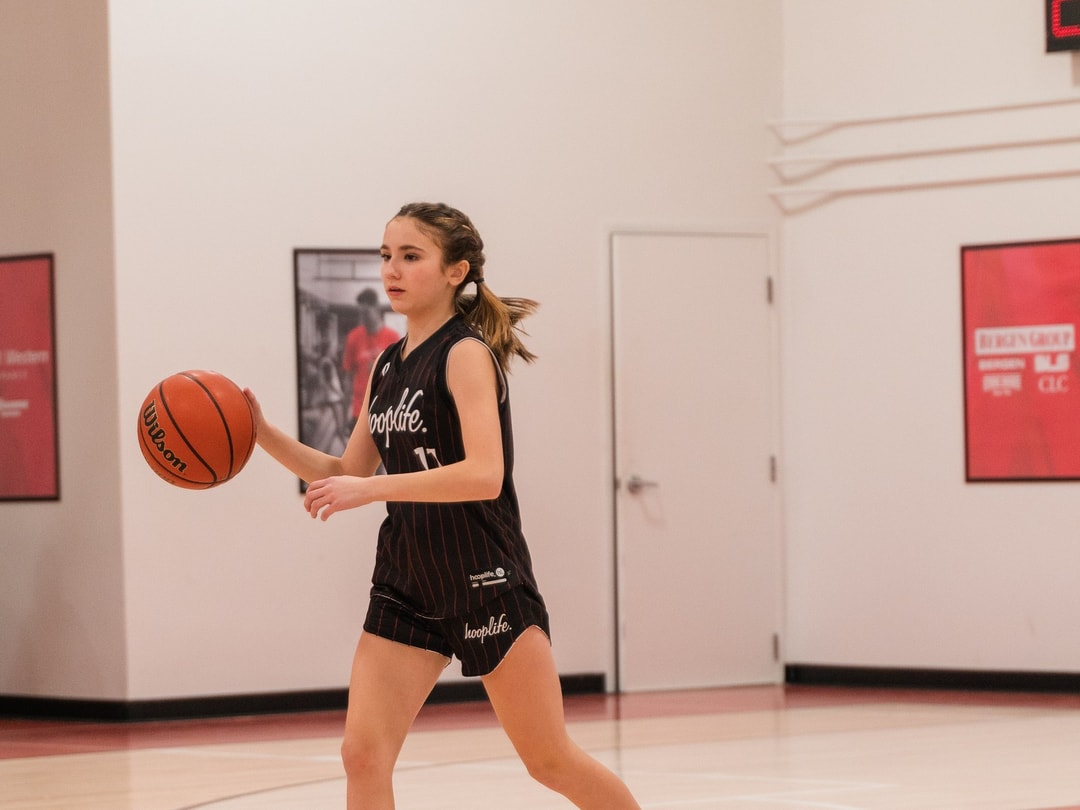 A girls division player bringing the ball up the floor