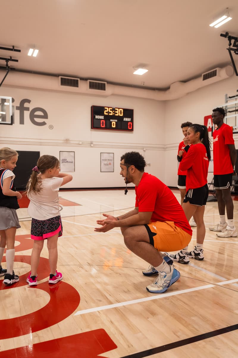 A HoopLife coach kneeling at eye level with two Young Stars girls