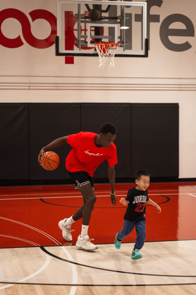 A HoopLife coach demonstrating a dribble as a Young Stars boy runs alongside