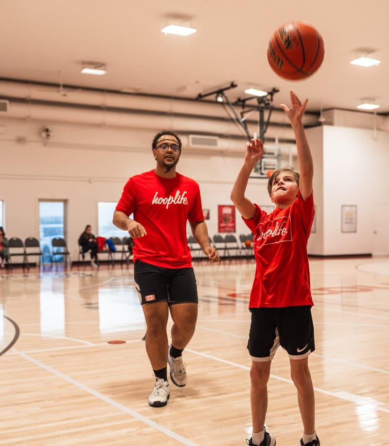 A player getting shots up with a coach rebounding